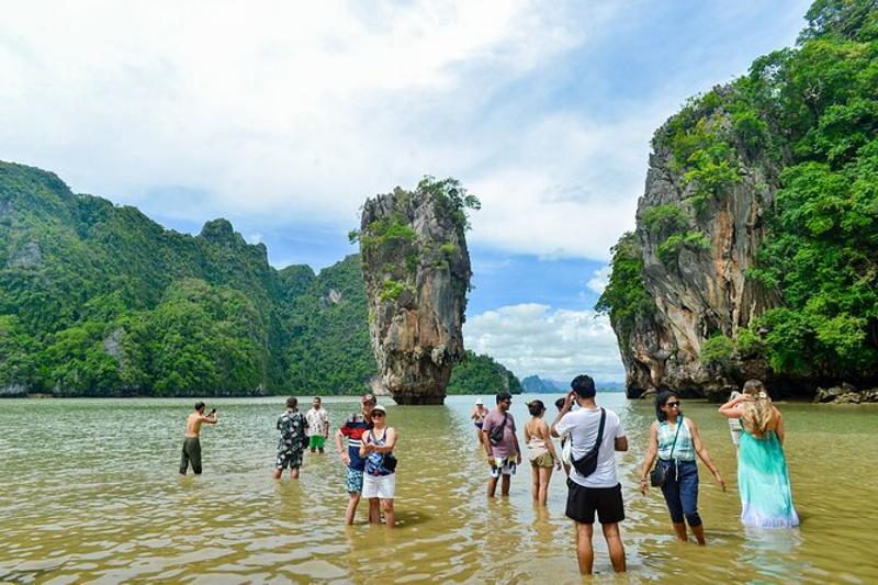 Group of tourists posing in front of James Bond Island´s famous rock formation, part of a Jame