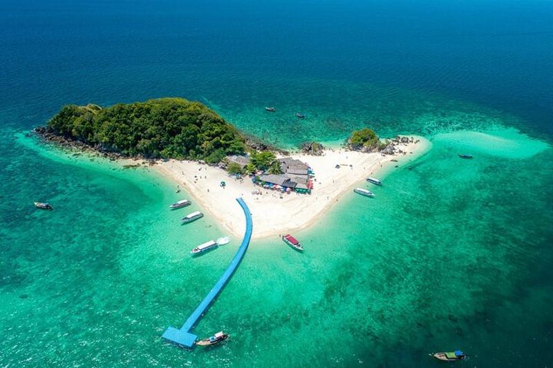  A tropical beach in Phuket with clear turquoise waters, palm trees, and boats docked along the shor
